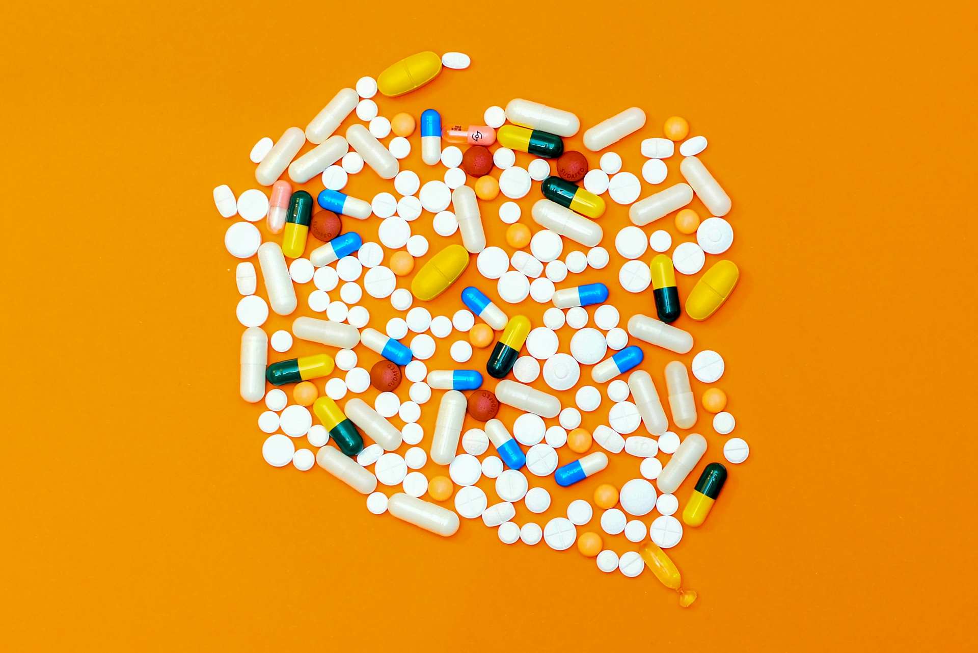 A variety of pills on an orange surface. Medication side effects can cause home care clients to have falls in their home.