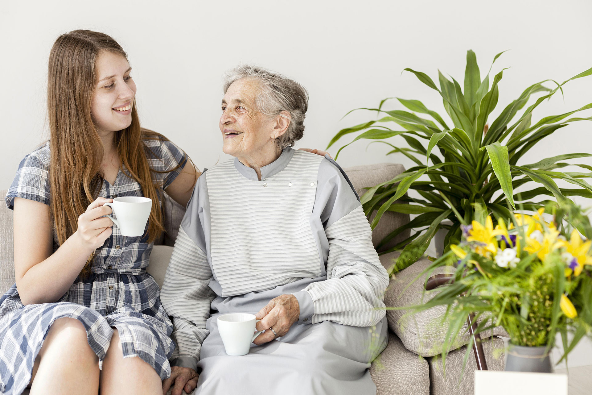 A home carer laughing and chatting over a cup of tea with her care client.