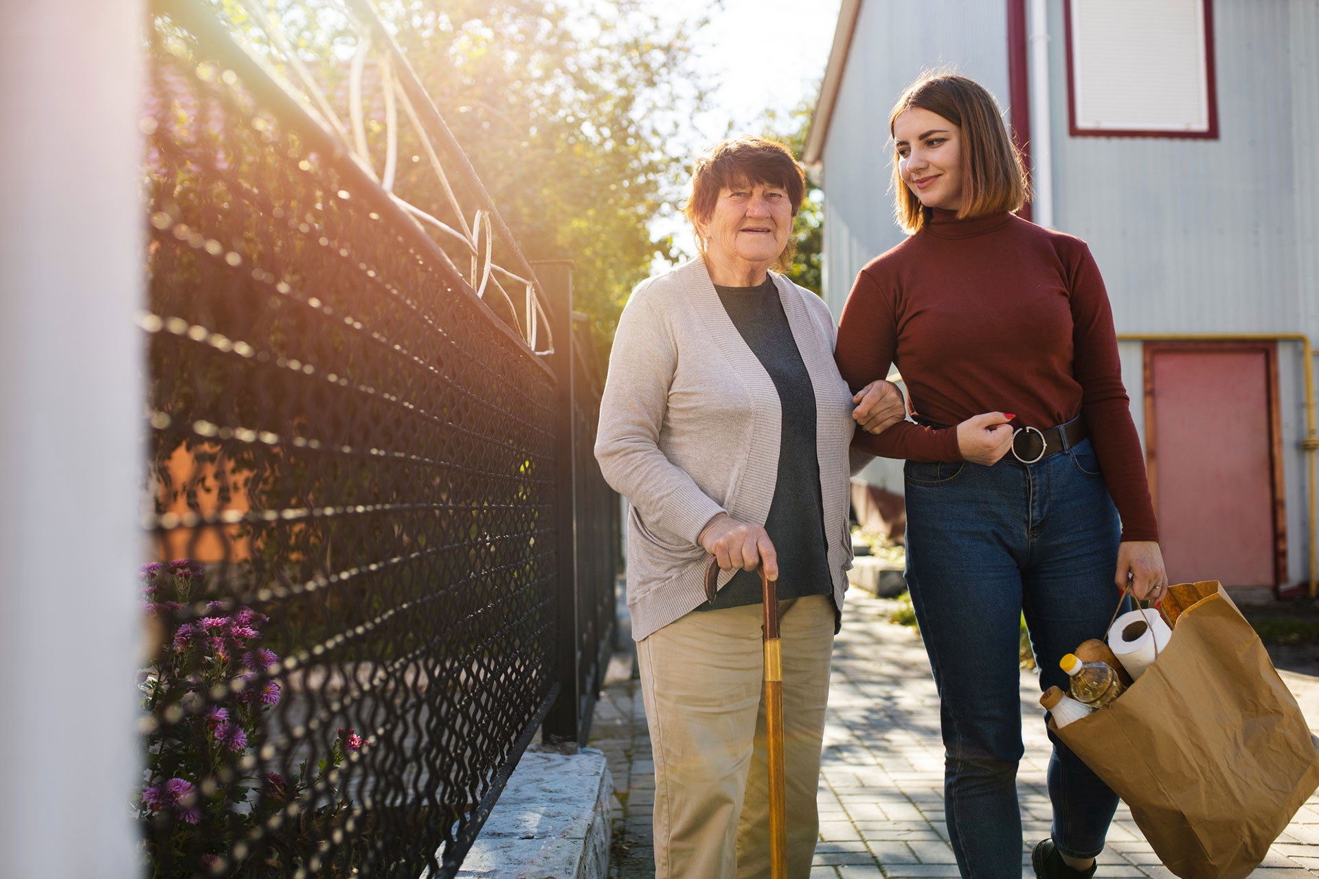 An elderly lady being helped with her shopping by her home carer.
