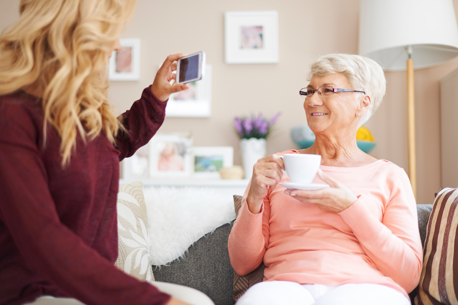 A grandmother chatting to relatives via a video call being filmed by her granddaughter on a smart phone.