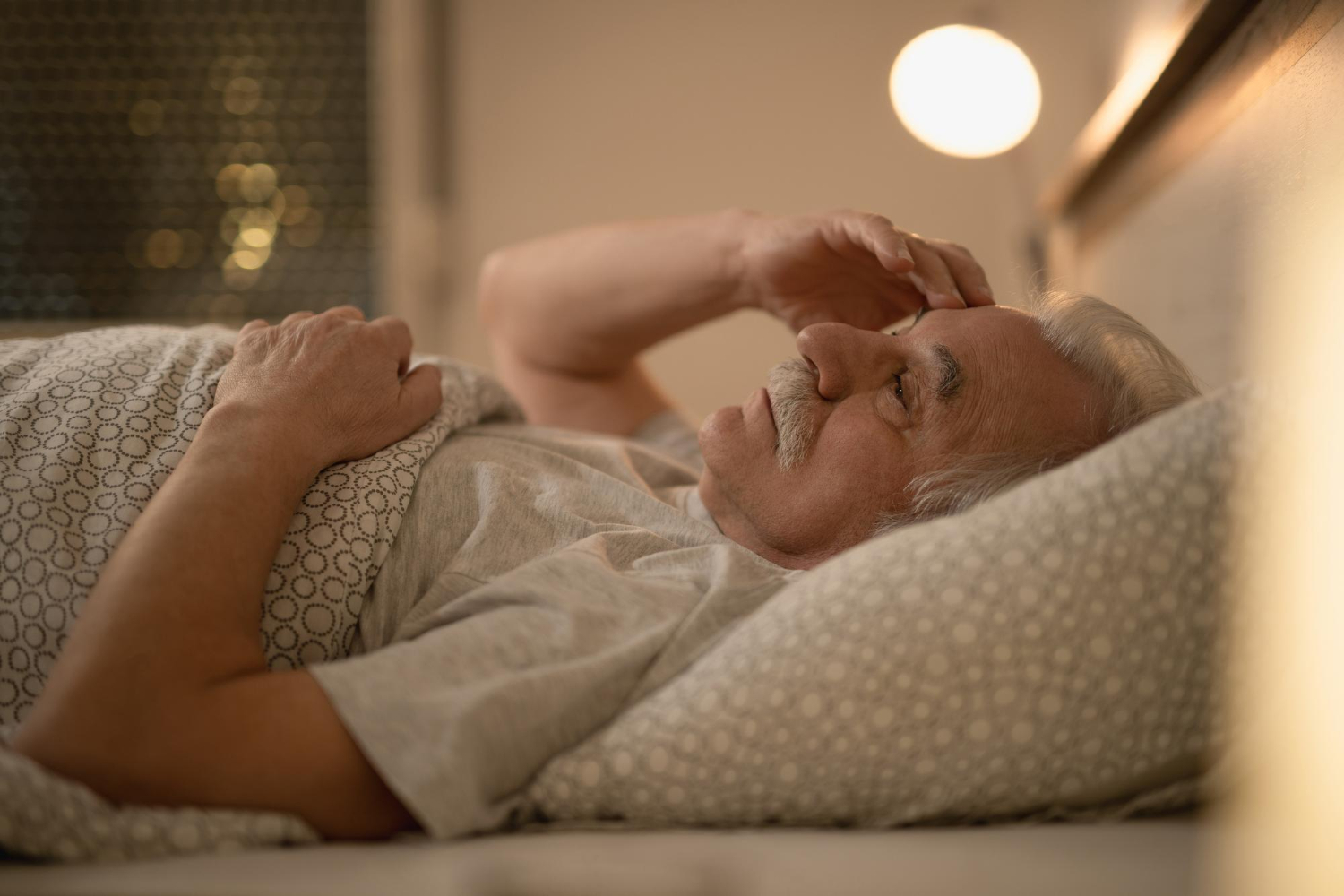 An elderly man with limited mobility lying in bed and looking worried. Physical dependence can feel like a loss of control.