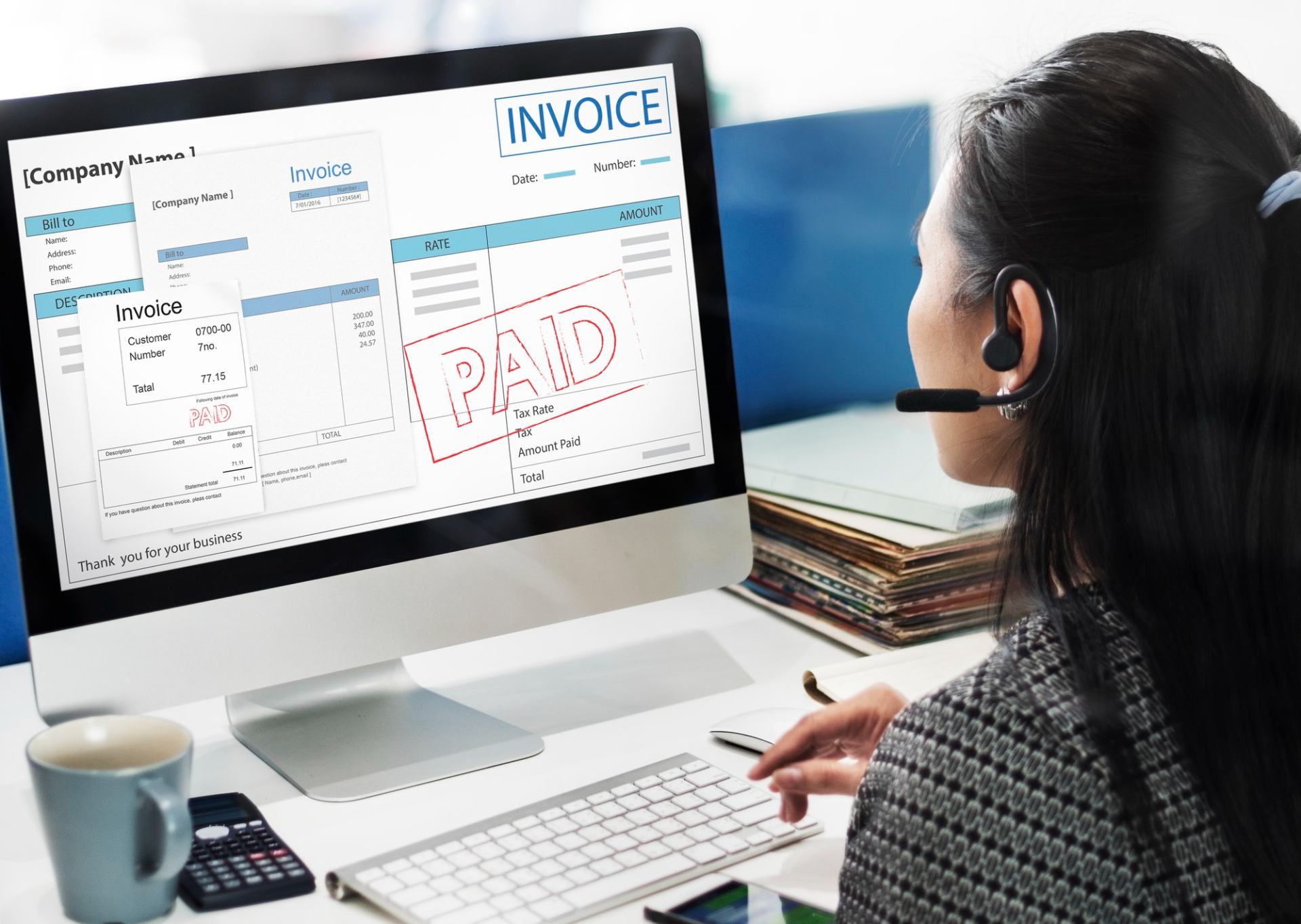 A UK home care agency owner using automation for her invoicing. Her laptop has an invoice on-screen with Paid stamped across it.