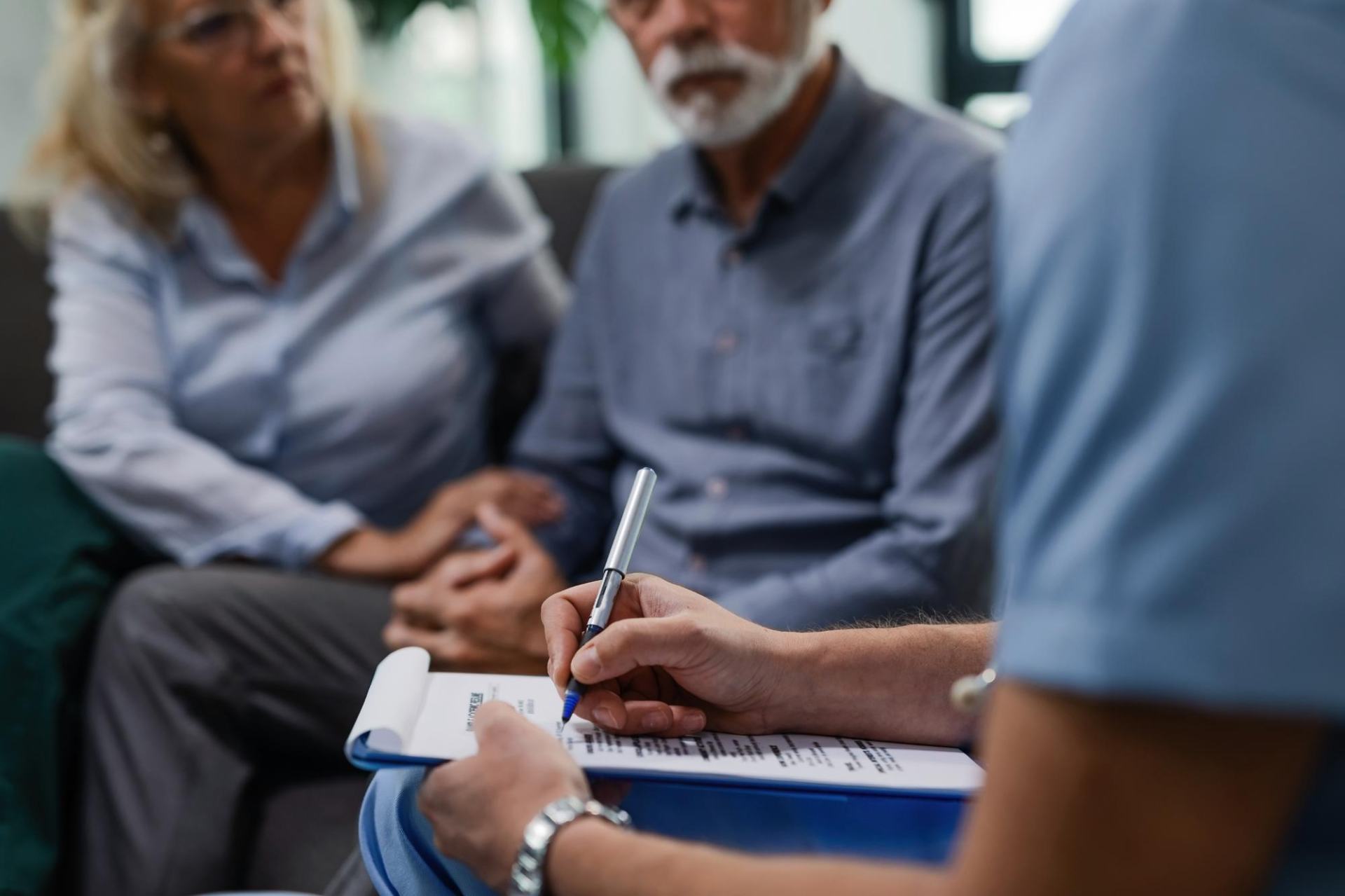 A home carer discussing a care plan with a client who has complex needs. A family member is present too, reassuring her loved one. A home carer discussing a care plan with a client who has complex needs. A family member is present too, reassuring her loved one.
